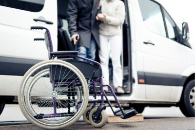 Personne à mobilité réduite qui descend d'un transport adapté.